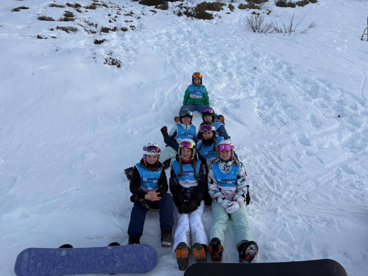 Snowboardkurs sitzend im Schnee